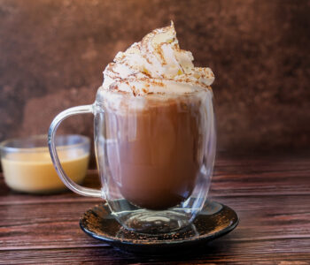Chocolat chaud avec chantilly et cacao dans une tasse en verre