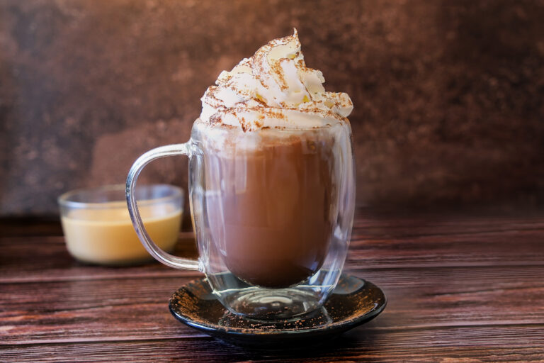 Chocolat chaud avec chantilly et cacao dans une tasse en verre