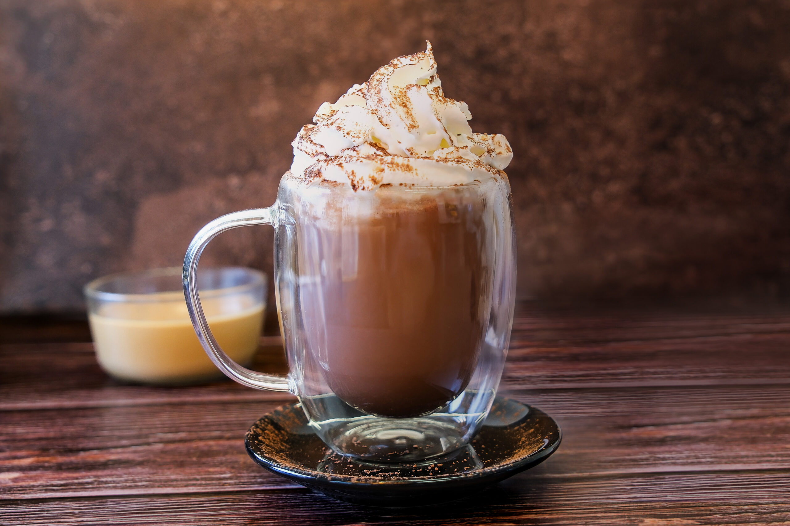 Chocolat chaud avec chantilly et cacao dans une tasse en verre