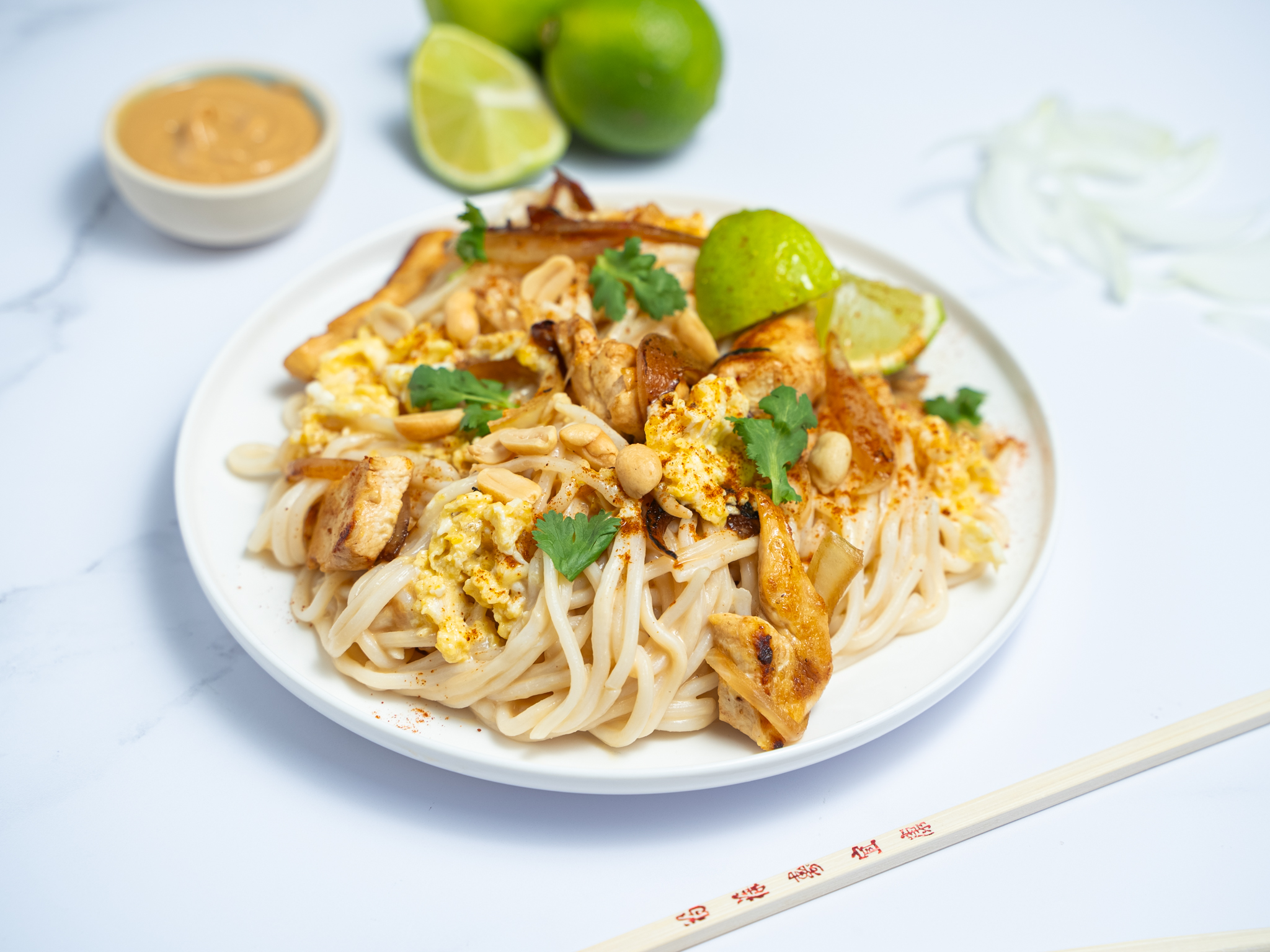 Nouilles sautées au poulet, œufs, cacahuètes et citron vert
