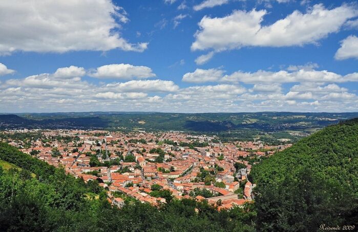 Vue panoramique d'une ville aux toits rouges entre deux collines verdoyantes